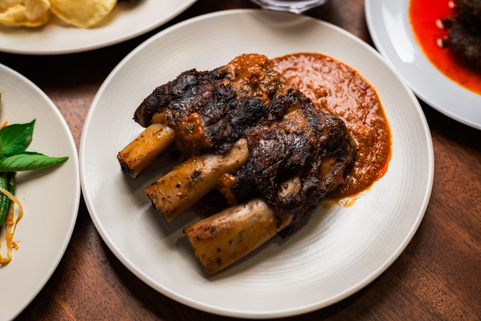 Delicious Indonesian beef ribs served with a spicy sauce, captured on a wooden table in Jakarta.