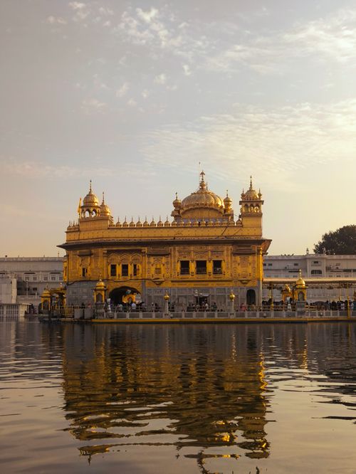Free Scenic view of the Golden Temple in Amritsar reflected in a calm lake at sunset. Stock Photo