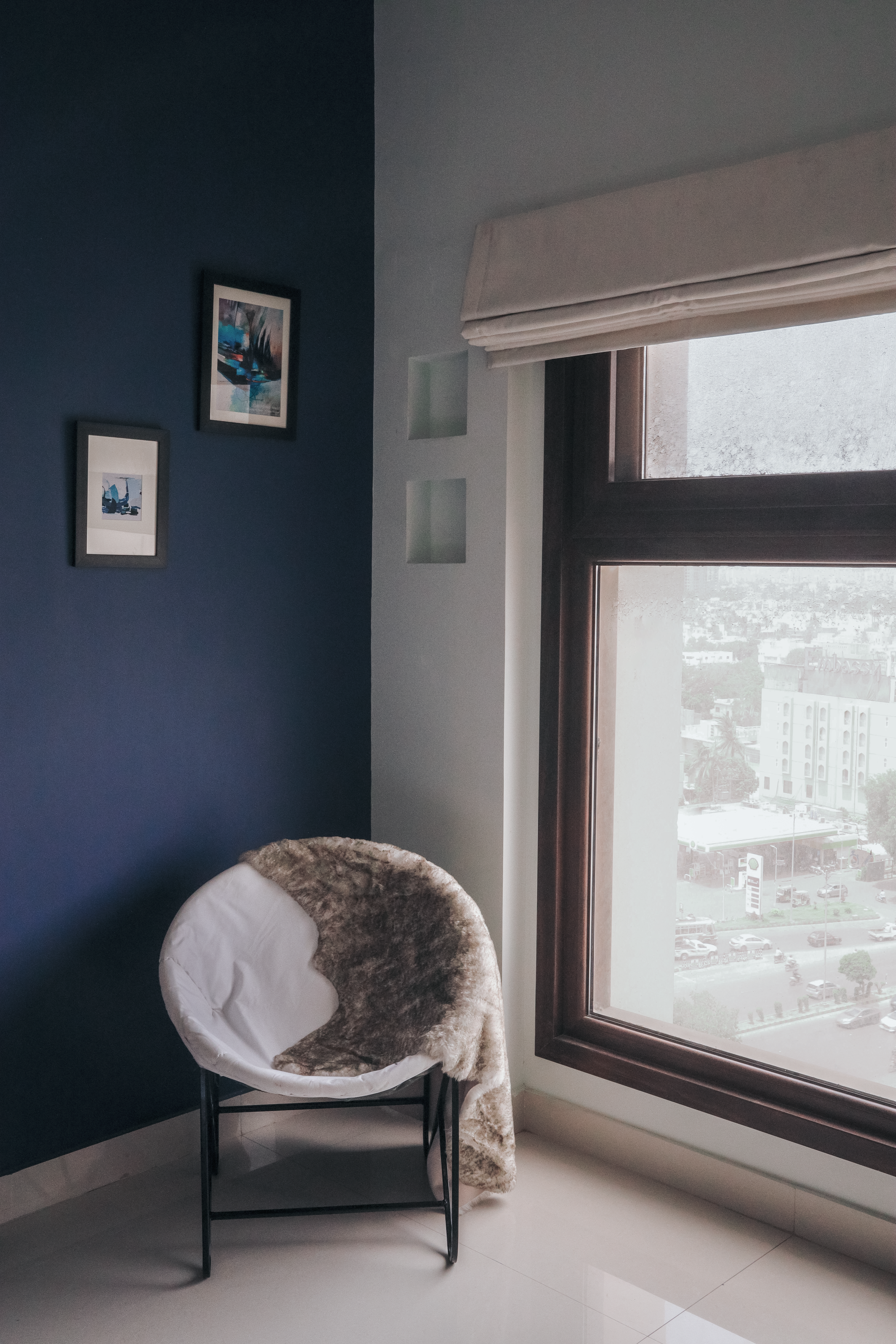 A modern interior with a cozy chair by a window, decorated with elegant wall art.