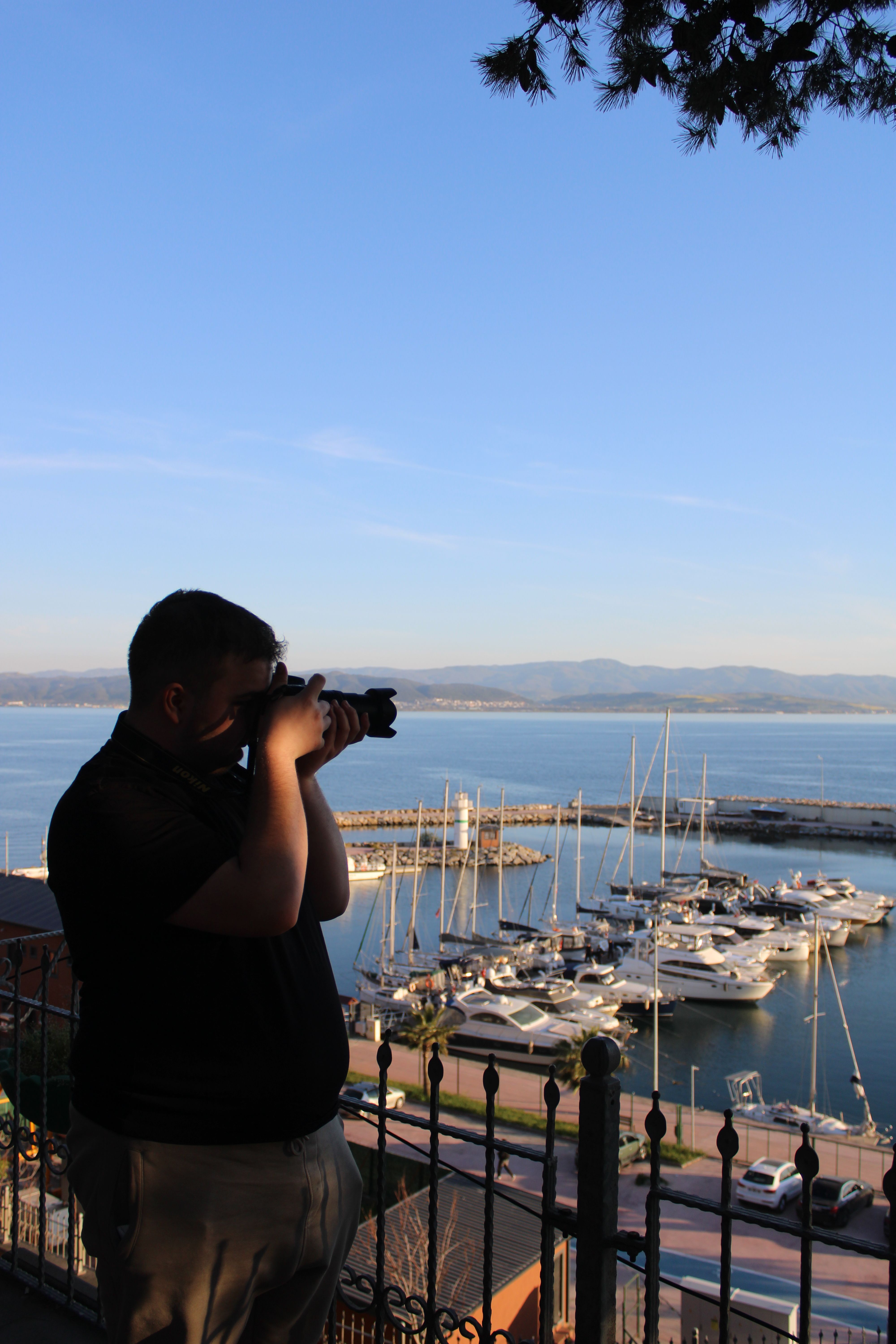 A photographer taking a picture of a beautiful marina during daytime.