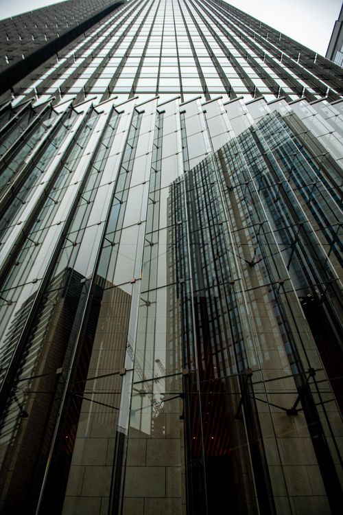 Free Low-angle view of a modern glass skyscraper reflecting the urban cityscape in Tokyo, Japan. Stock Photo