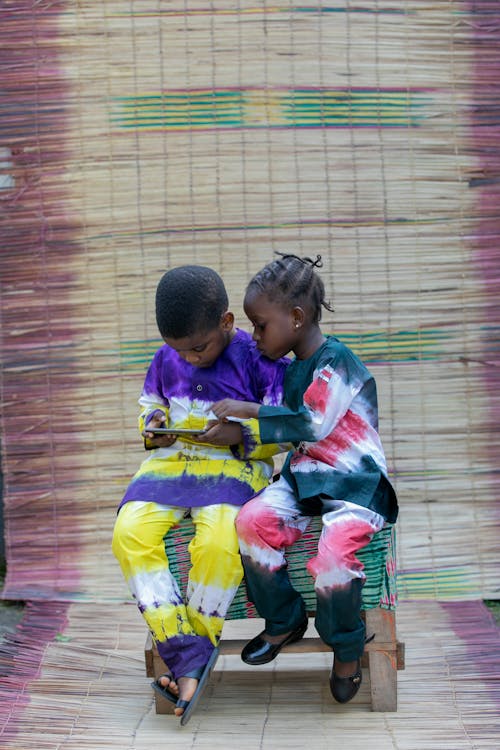 Black children sitting on stool and using smartphone