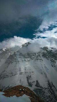 Snow-capped mountains with clouds and blue sky creating a dramatic winter scene.