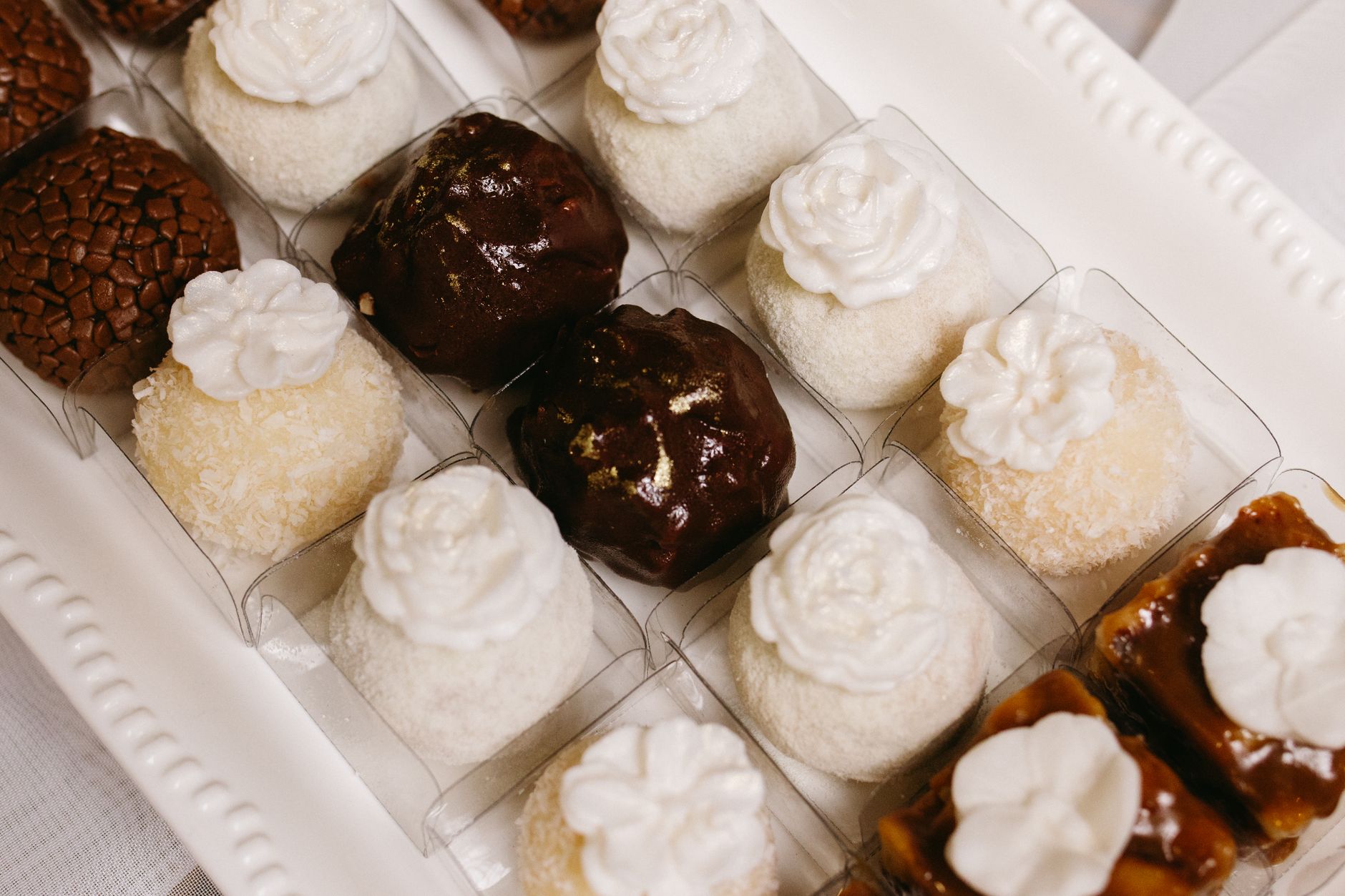 A variety of Brazilian brigadeiros and coconut truffles arranged on a white tray, perfect for party desserts.