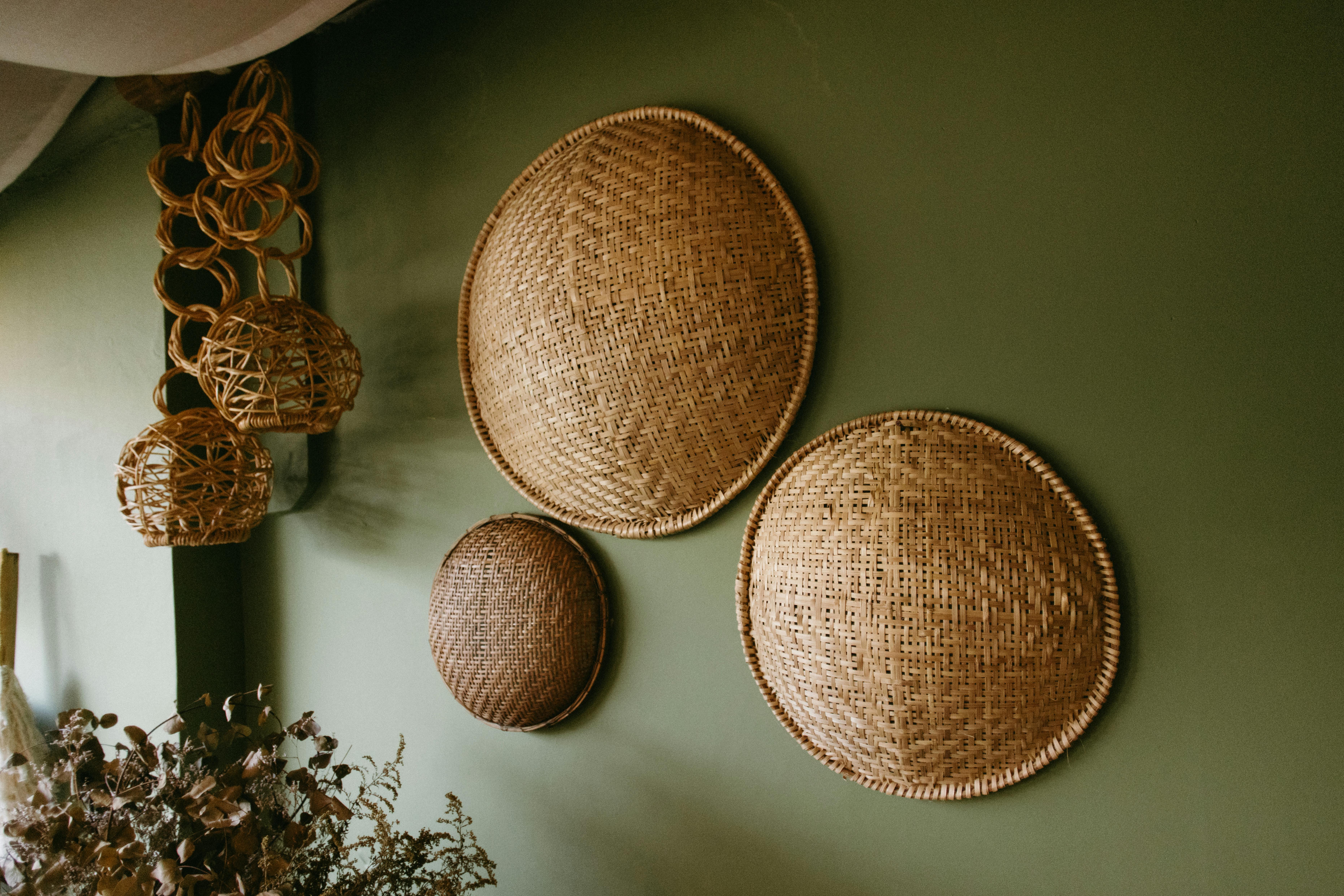Paniers en bambou tressés vintage accrochés sur mur vert, décoration murale en paille artisanale