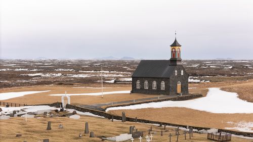 Free A scenic view of a historical church and graveyard surrounded by Icelandic nature during early spring in Suðurnesjabær, Iceland. Stock Photo