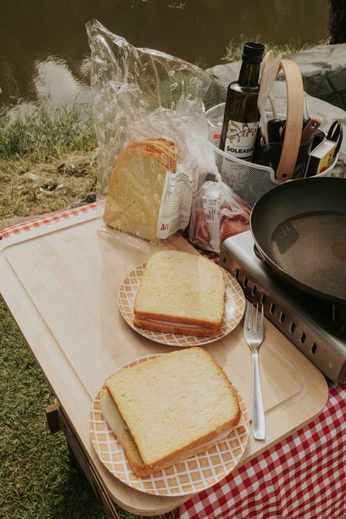 Free A peaceful outdoor picnic setup with sliced bread and frying pan, perfect for camping or a riverside meal. Stock Photo