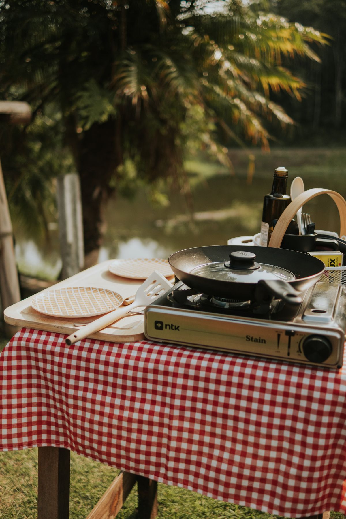 Portable outdoor cooking setup beside a peaceful pond