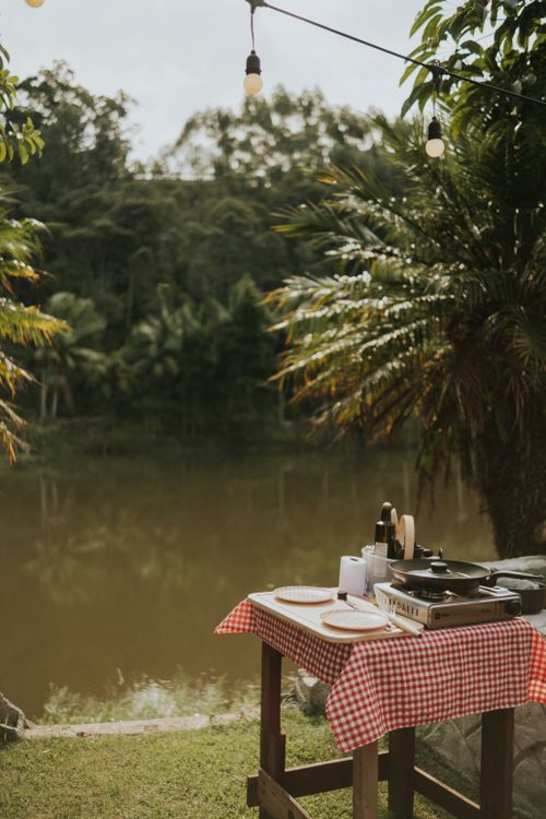 Free A charming outdoor dining table near a tranquil riverside, perfect for a picnic or camping experience. Stock Photo
