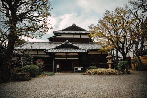 Free A traditional Japanese house surrounded by autumn foliage, showcasing cultural architecture. Stock Photo