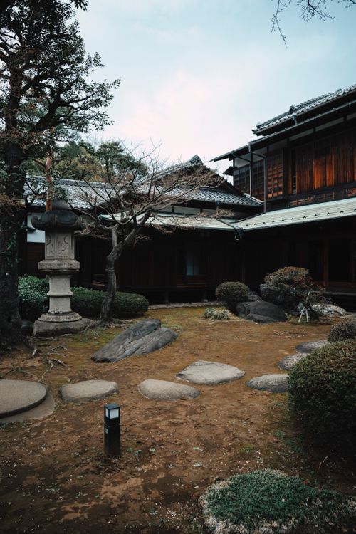 Free Japanese garden featuring a stone lantern and traditional wooden architecture, perfect for travel and cultural themes. Stock Photo