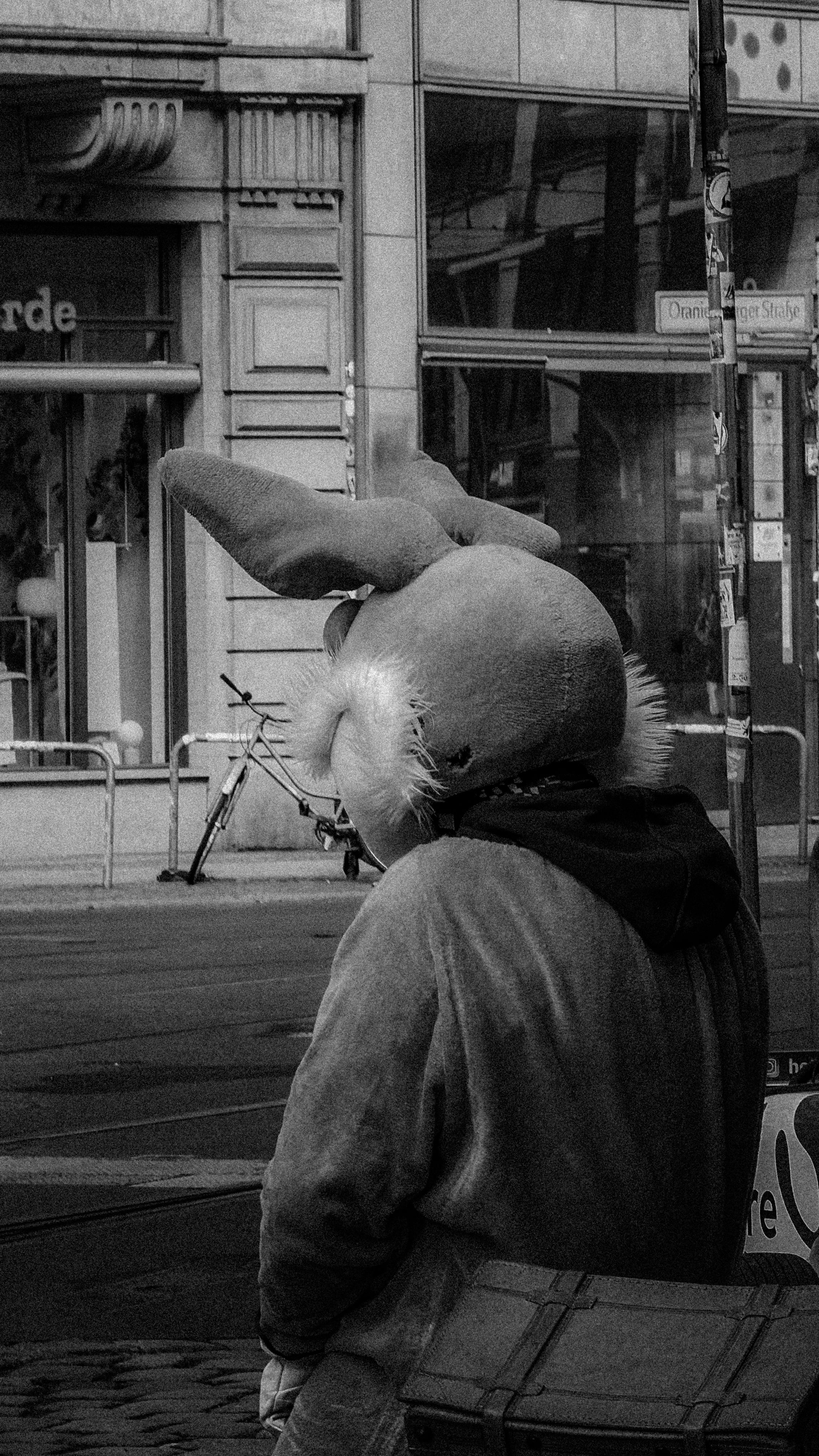 A person in a bunny costume stands on an urban street captured in black and white.