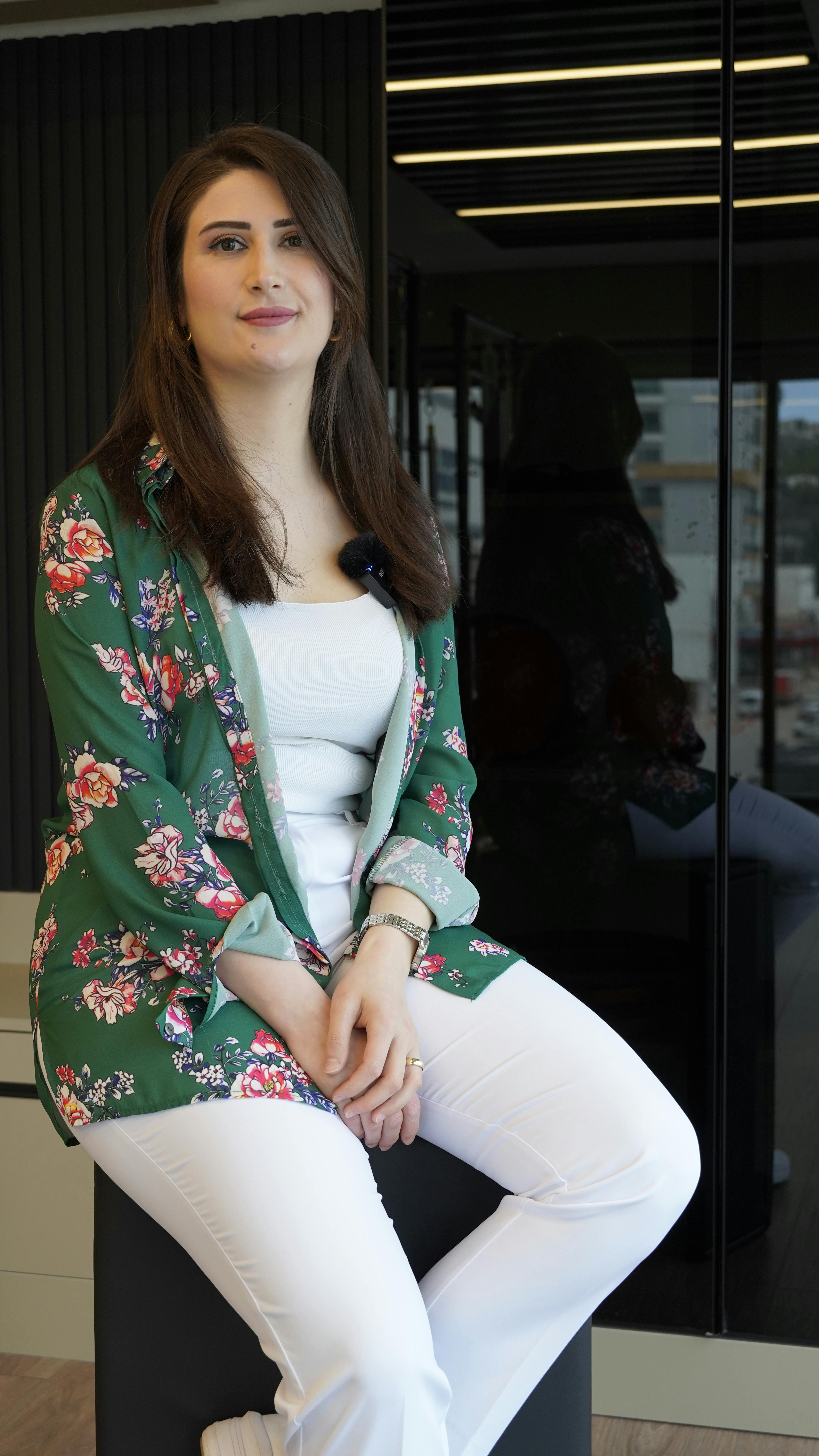 Stylish woman in floral blazer poses confidently indoors, reflecting modern fashion style.
