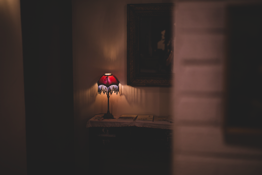 A warm, moody interior featuring a vintage lamp casting a soft glow on a table.