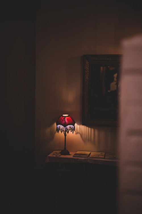 Free Vintage table lamp casting a warm glow in a cozy, dimly lit room. Stock Photo