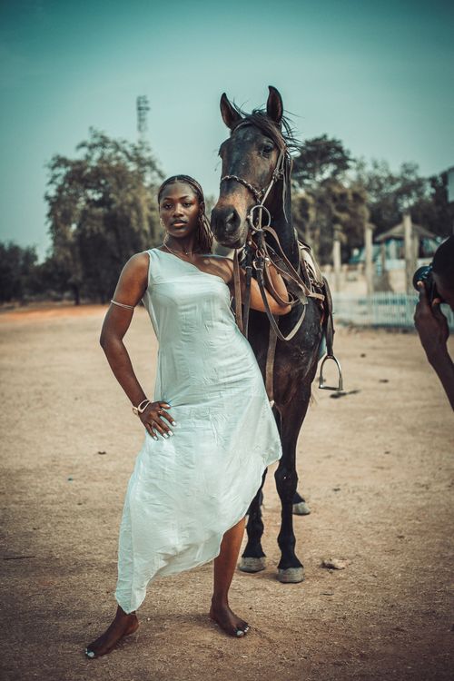 Free Stylish woman in a flowing dress poses confidently with a horse outdoors, exuding grace and elegance. Stock Photo