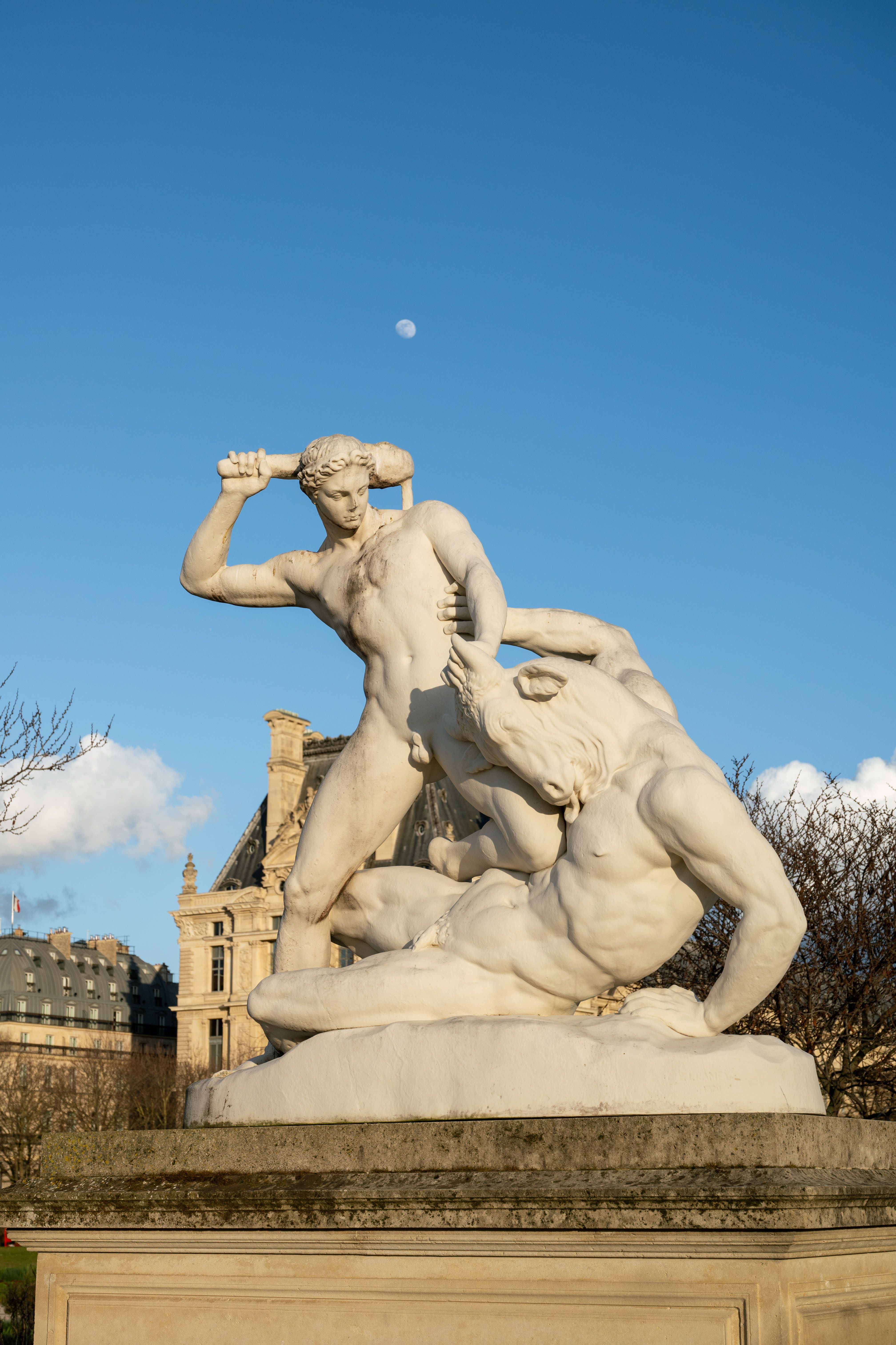 Statue of Theseus and the Minotaur against a clear blue sky in Paris.