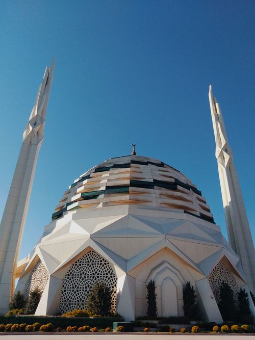 Free Modern mosque with unique dome and minarets against a clear blue sky, showcasing intricate design. Stock Photo