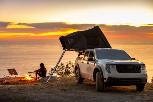 Explore outdoor camping with a rooftop tent overlooking the ocean at sunset. Ideal for adventure seekers.