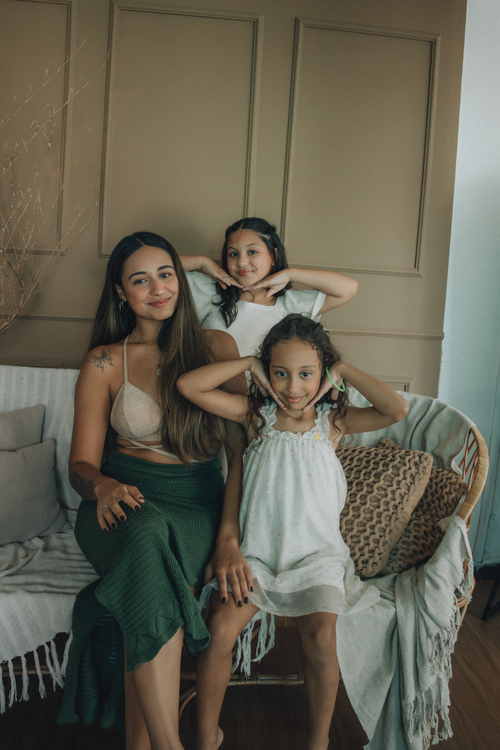 Free A mother and two daughters sharing a joyful moment indoors on a couch. Stock Photo