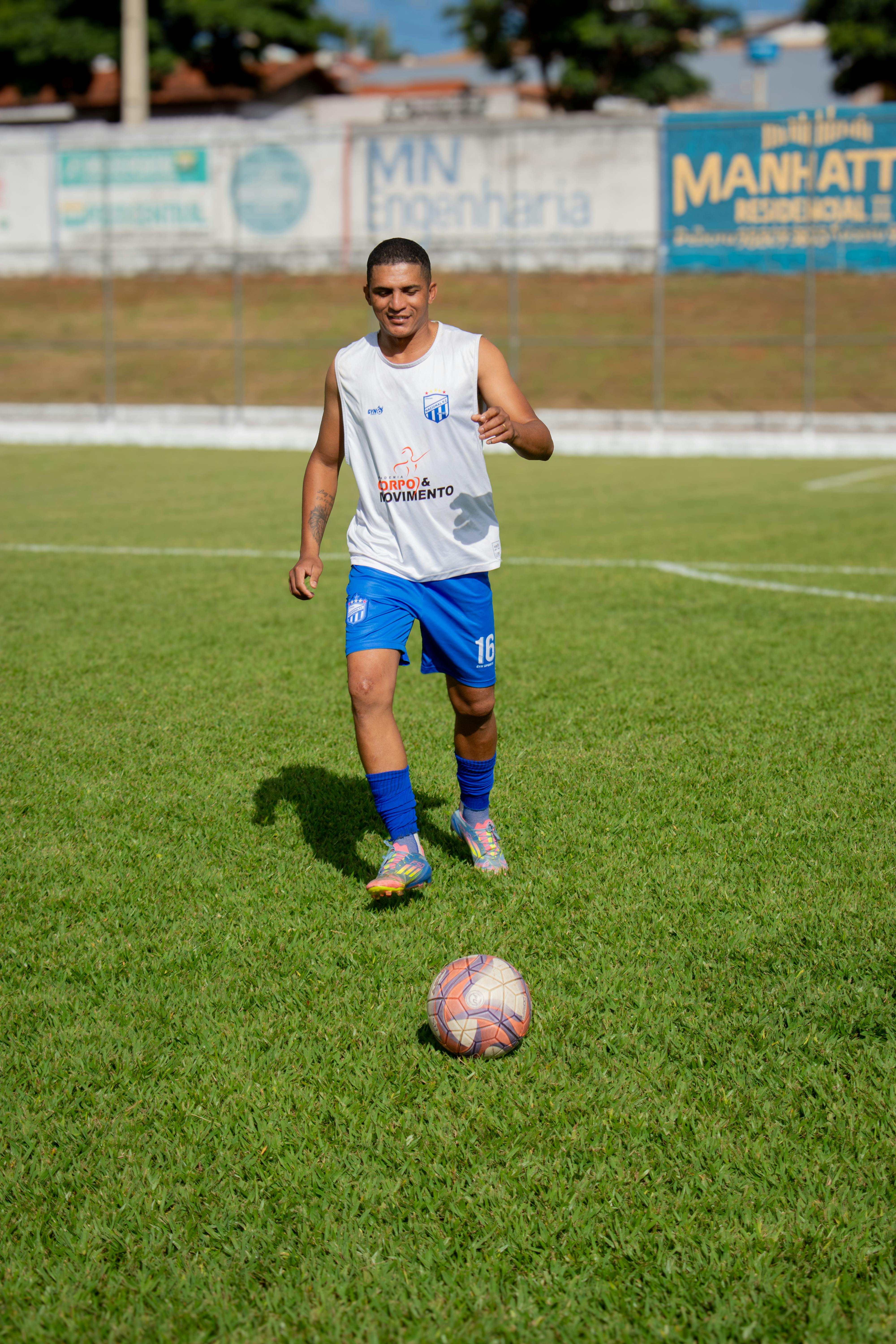 A young soccer player practices dribbling on a green grass field on a sunny day.