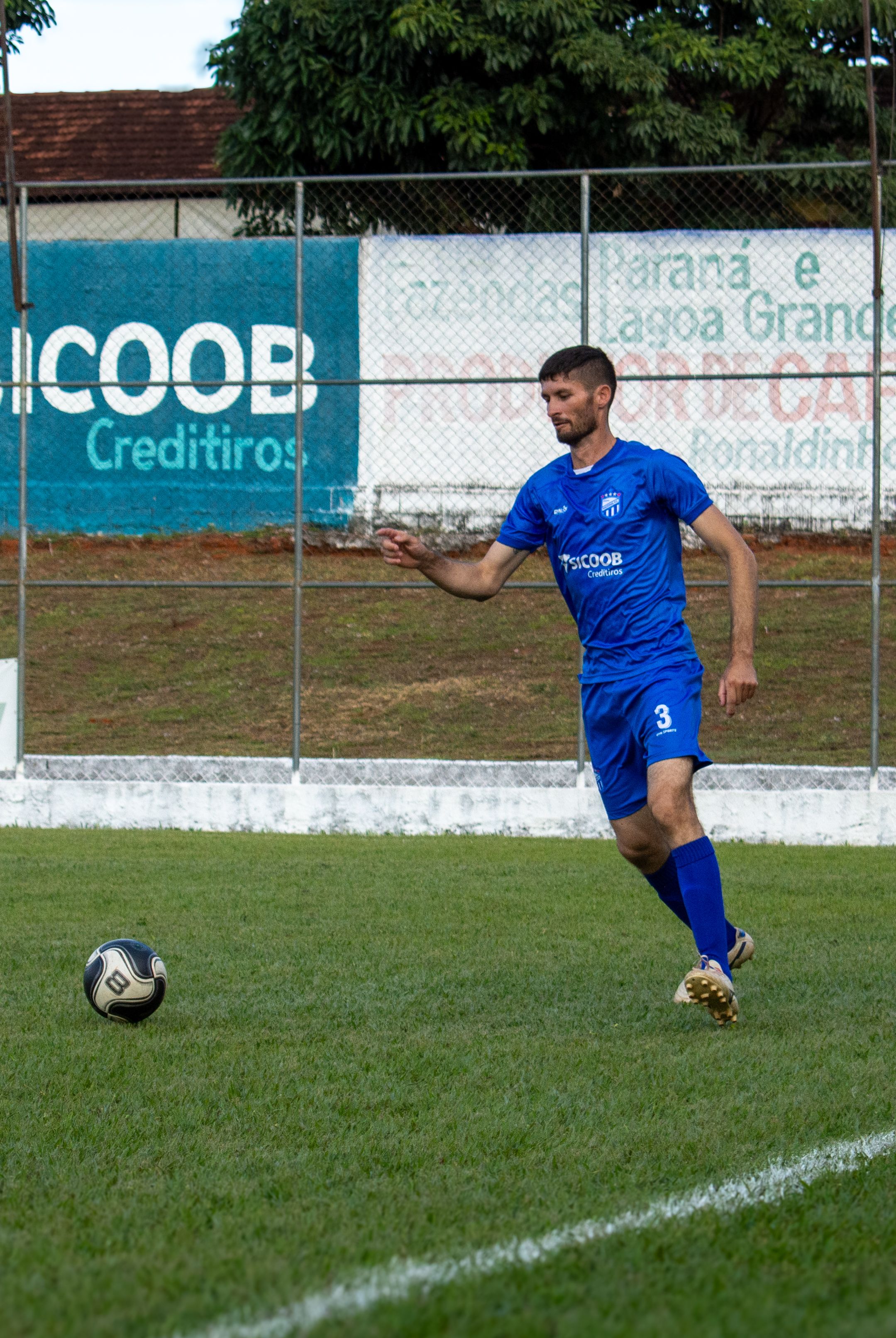 A soccer player in blue uniform about to kick a soccer ball on a grassy field.
