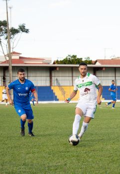 Players in blue and white kits in action during a soccer match on a green field.