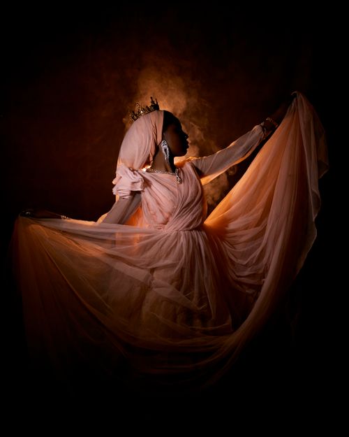 Free Stunning artistic portrait of a woman in elegant attire with a crown, captured in warm lighting. Stock Photo