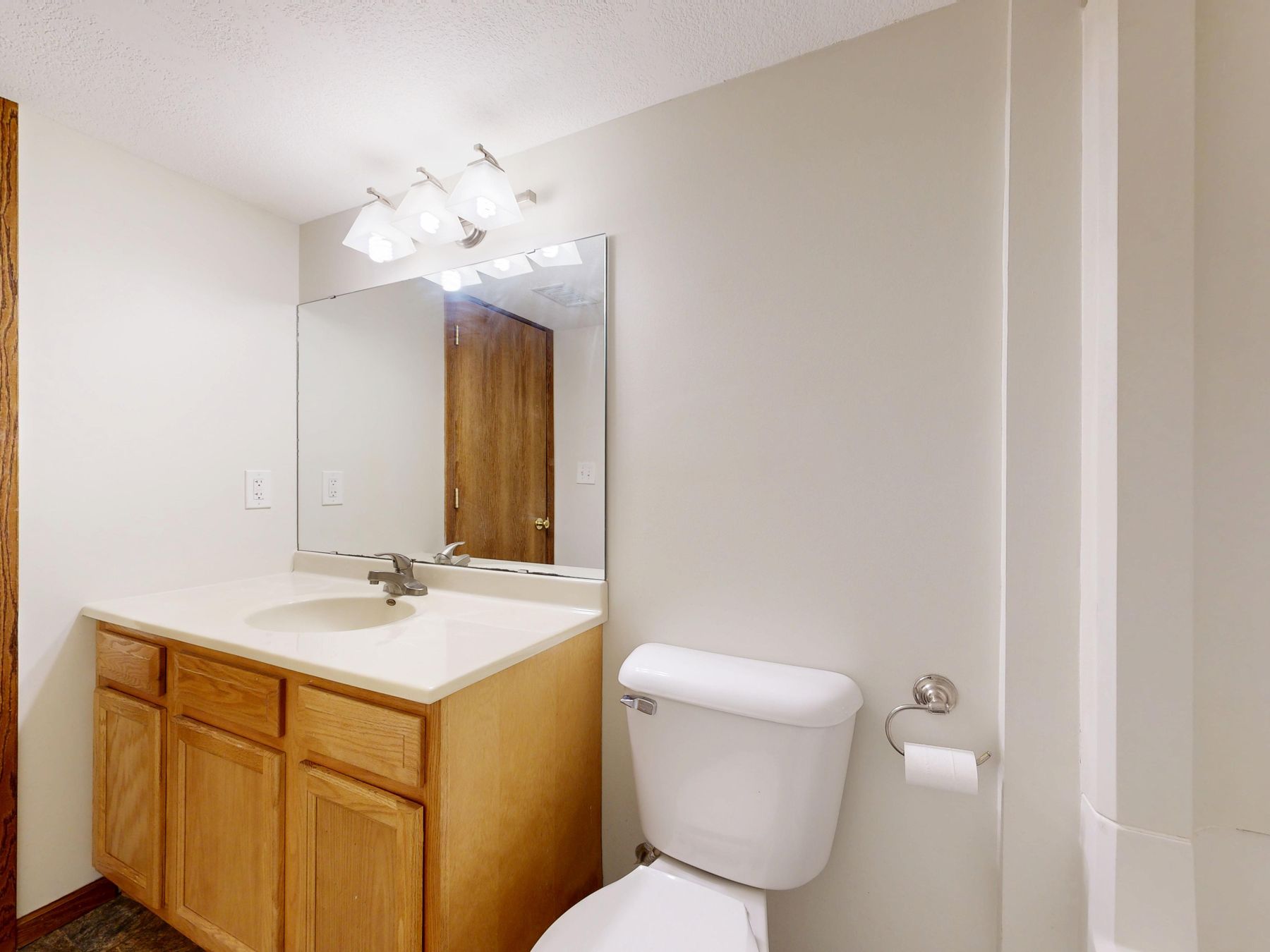 Broad bathroom mirror reflecting pale finishes and practical light