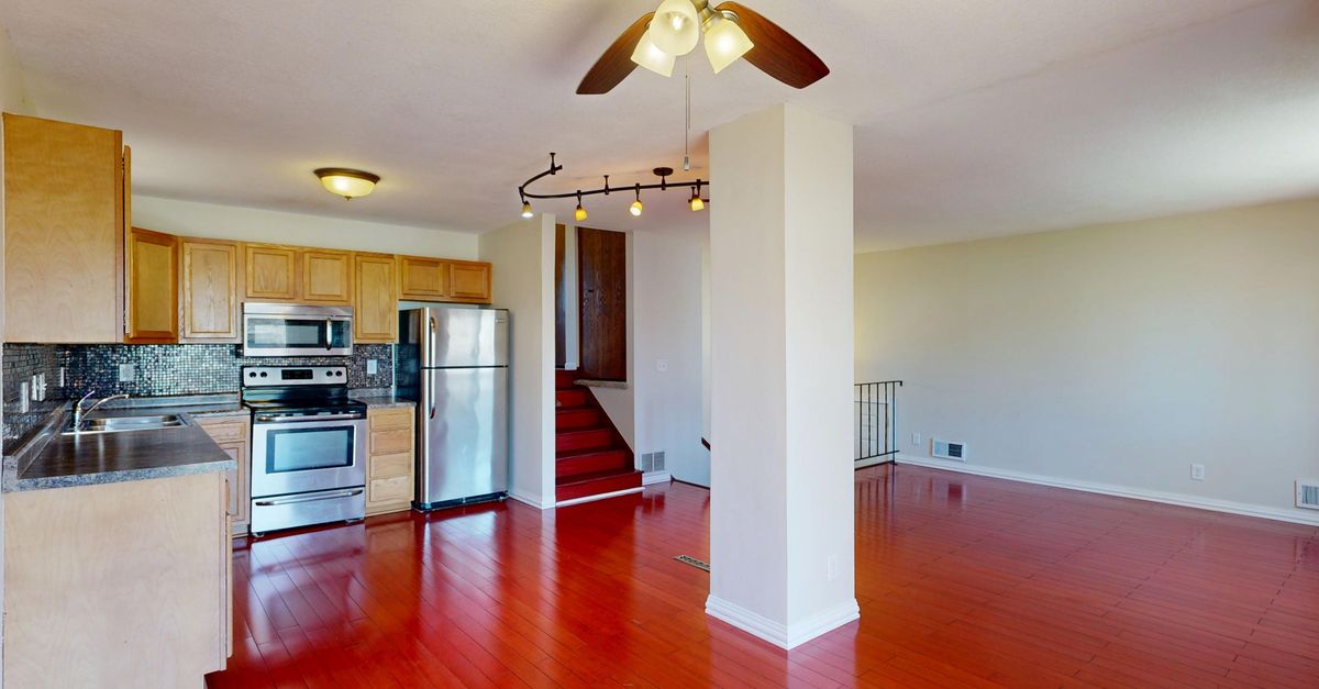 Spacious open-plan kitchen and living room with wood floors and ceiling fan.