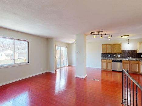 Spacious empty kitchen with hardwood floors and natural light.