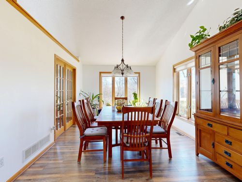 Free Bright dining room with wooden table, chairs, and cabinet under a hanging light fixture. Stock Photo