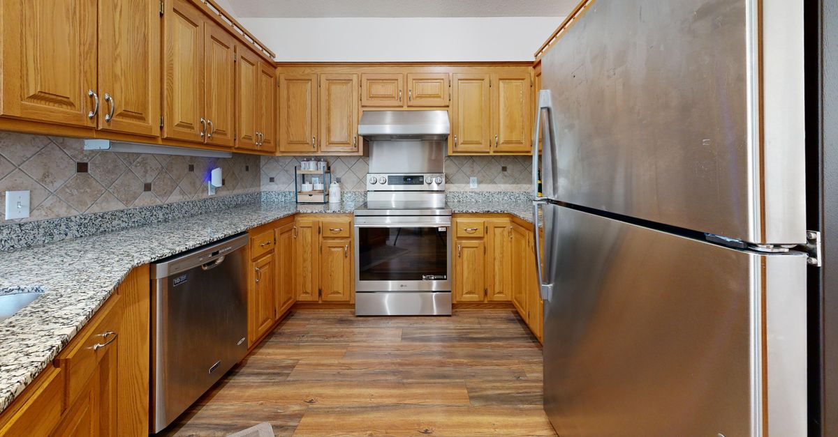 A well-lit kitchen featuring stainless steel appliances and wooden cabinets.