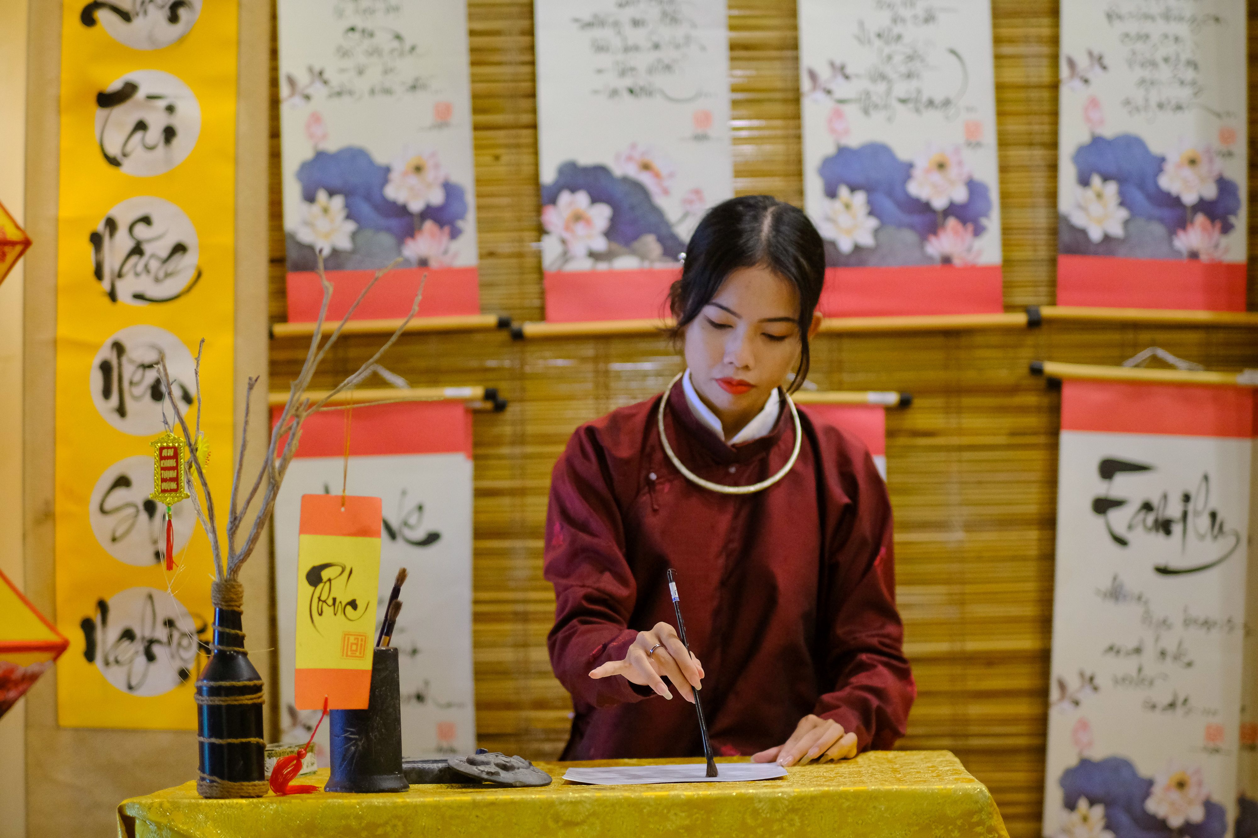 Woman practicing traditional calligraphy in Hue, Vietnam, showcasing cultural heritage.