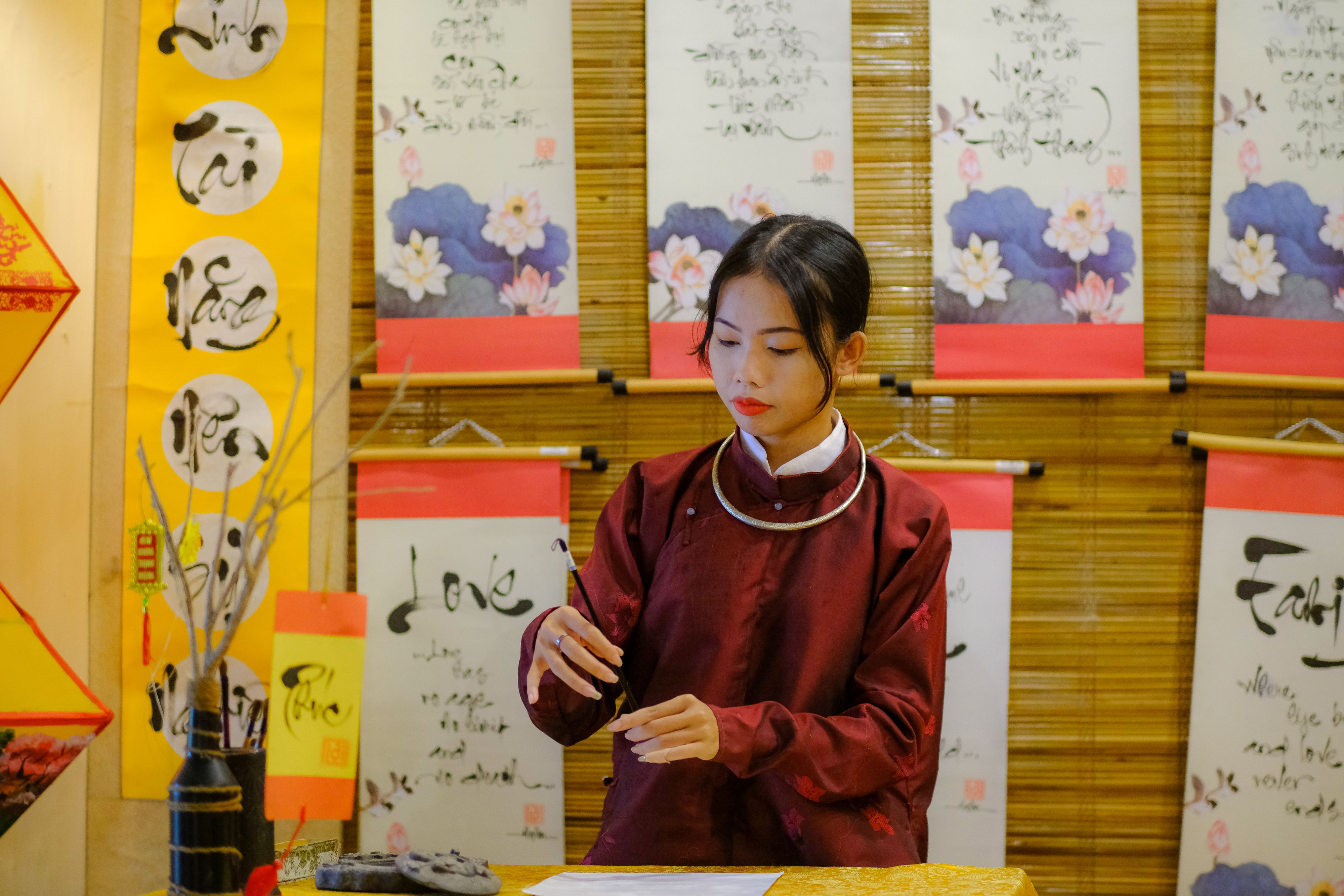 Woman practicing calligraphy surrounded by Vietnamese art in Hue, Vietnam.