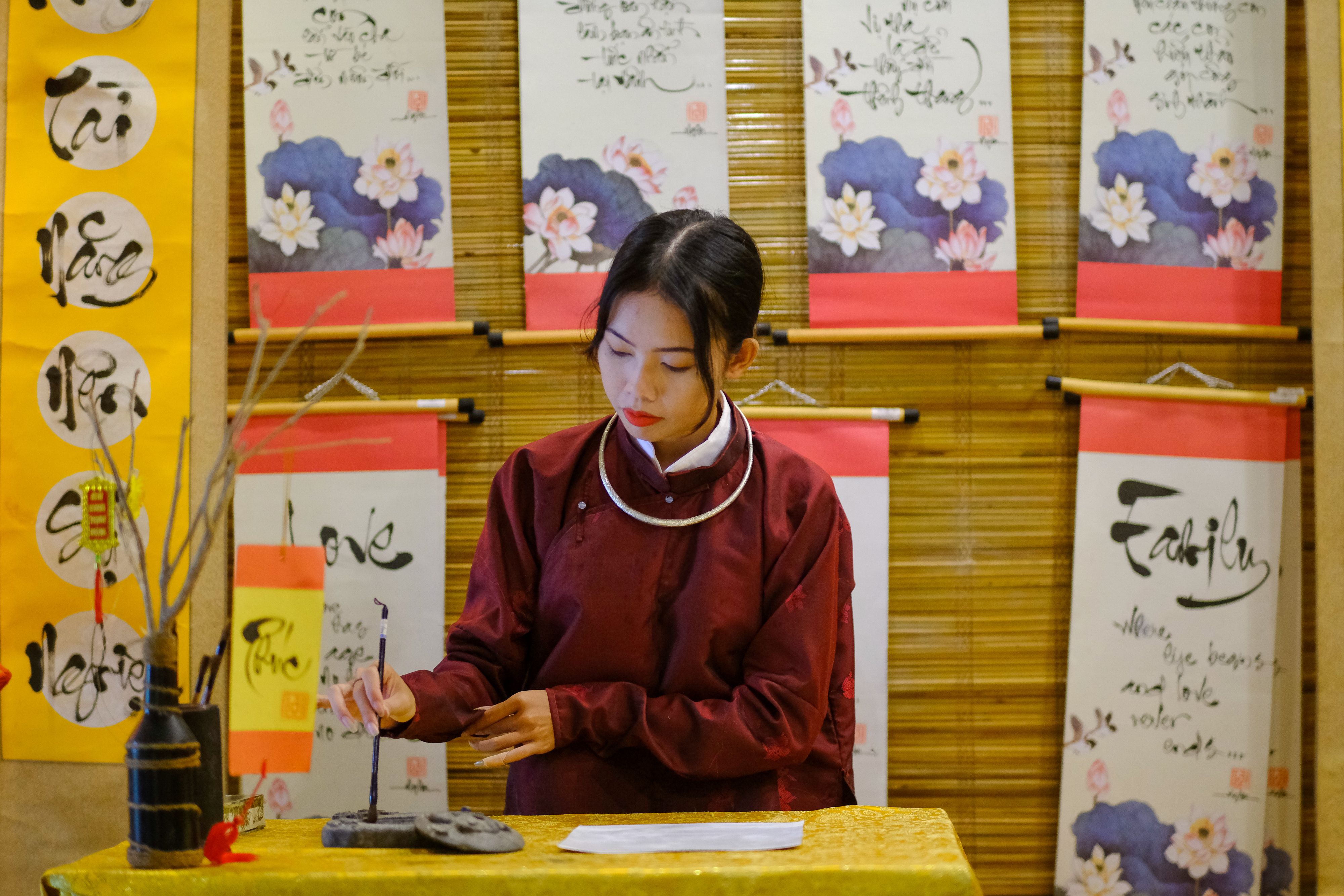 A woman in Hue, Vietnam, practicing traditional calligraphy indoors.