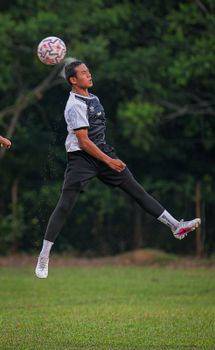 Dynamic shot of a soccer player jumping to head the ball during a game at Simpang Pertang, Malaysia.