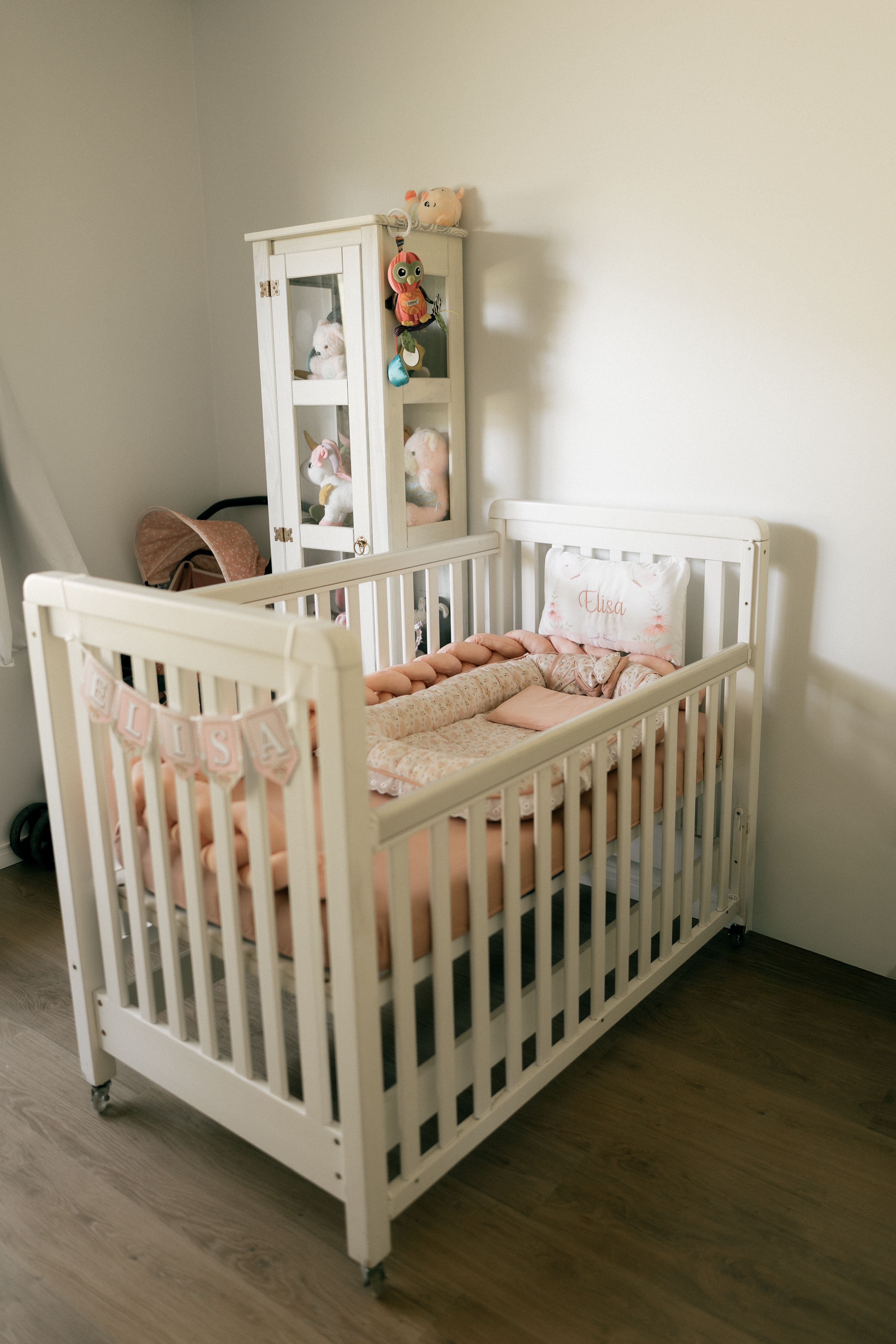 A warm and inviting baby nursery featuring a white crib adorned with plush blankets and stuffed toys, exuding comfort.