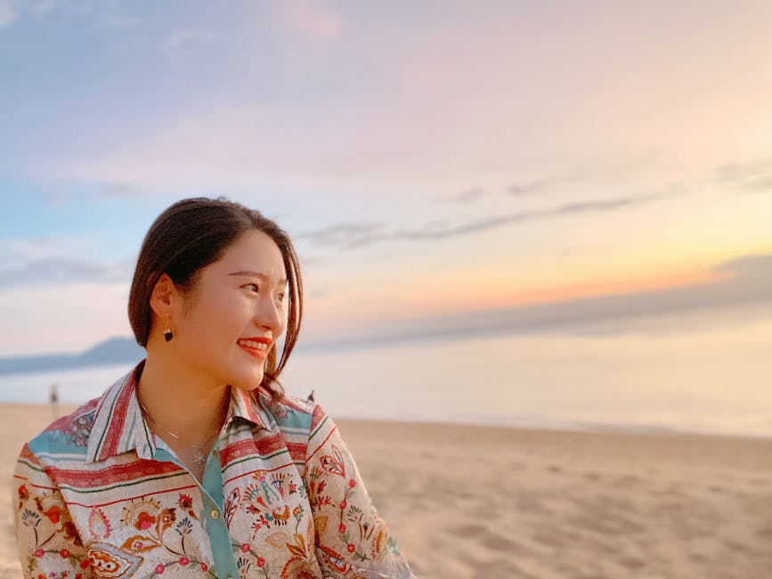 Smiling woman in a colorful shirt enjoying a serene beach sunset in Phuket, Thailand.