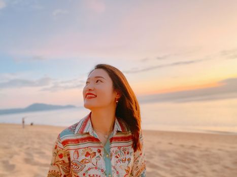 Asian woman enjoying a serene sunset at Phuket beach, Thailand.