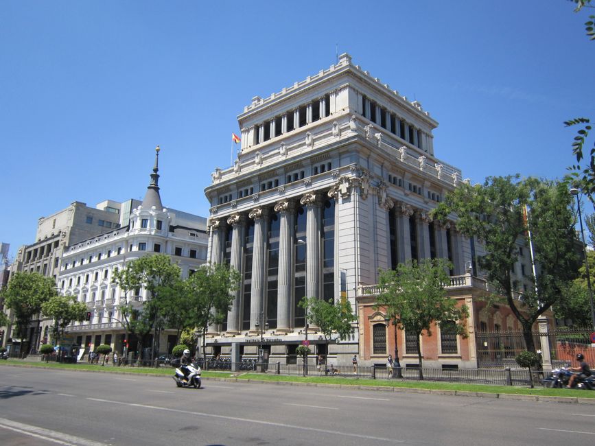 Majestuosos edificios bordean una soleada calle de Madrid, España, simbolizando la elegancia urbana.