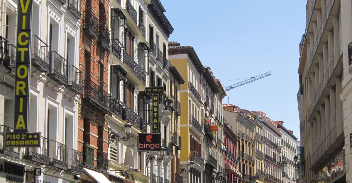 Vibrant street in Madrid showcasing classic Mediterranean architecture under a clear summer sky.