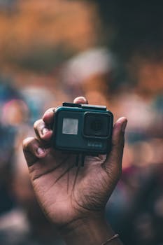 A hand holding an action camera with a blurred city background, highlighting spontaneity and adventure.