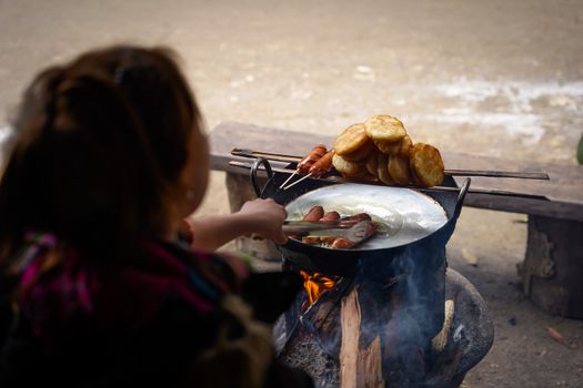A person cooking traditional Vietnamese street food on an outdoor stove in Mộc Châu, Vietnam.