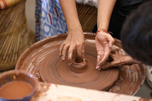 Close-up of hands sculpting clay on a pottery wheel, showcasing creative adult crafting.