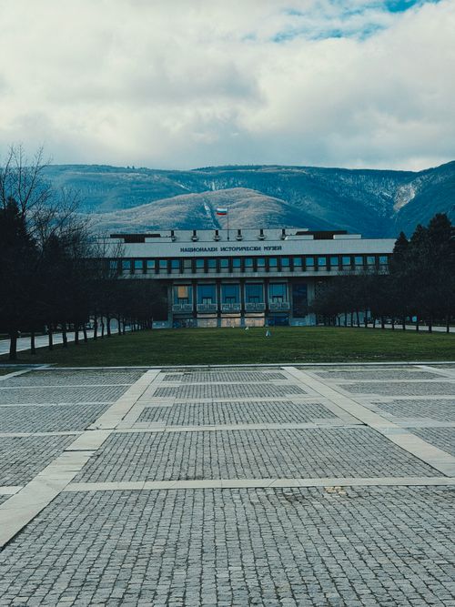 Free View of the National History Museum with a mountain backdrop in Bulgaria, featuring a pedestrian walkway. Stock Photo