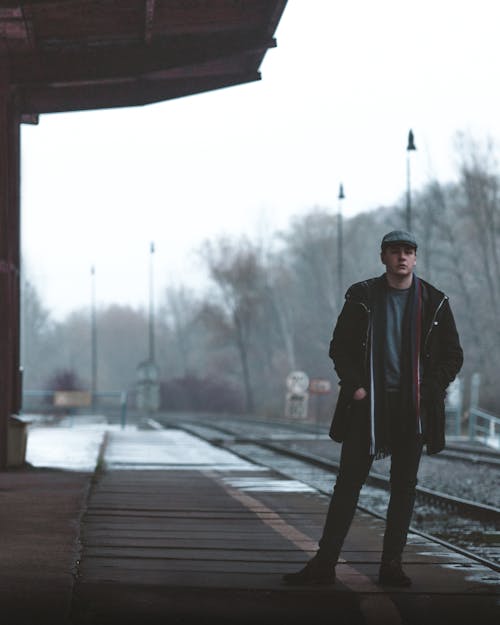 Unemotional man standing on railroad station platform on winter day