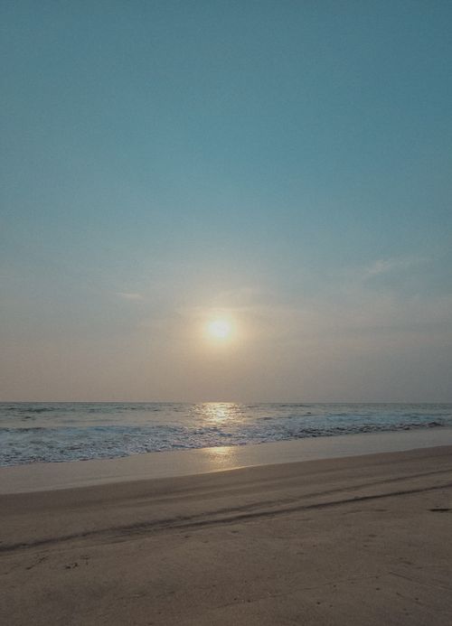 Free Tranquil sunrise over a serene ocean, casting reflections on the sandy beach. Stock Photo