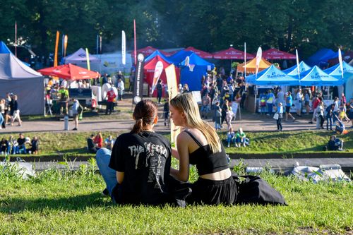 Free Two women sitting on grass at an outdoor festival in Pärnu, Estonia, enjoying a sunny day. Stock Photo