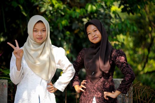 Free Two young women wearing traditional hijabs posing confidently in a lush outdoor environment. Stock Photo